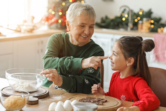 A grandmother and granddaughter baking together at a kitchen table