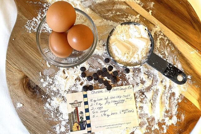 Eggs, flour and a handwritten recipe card on a wooden board